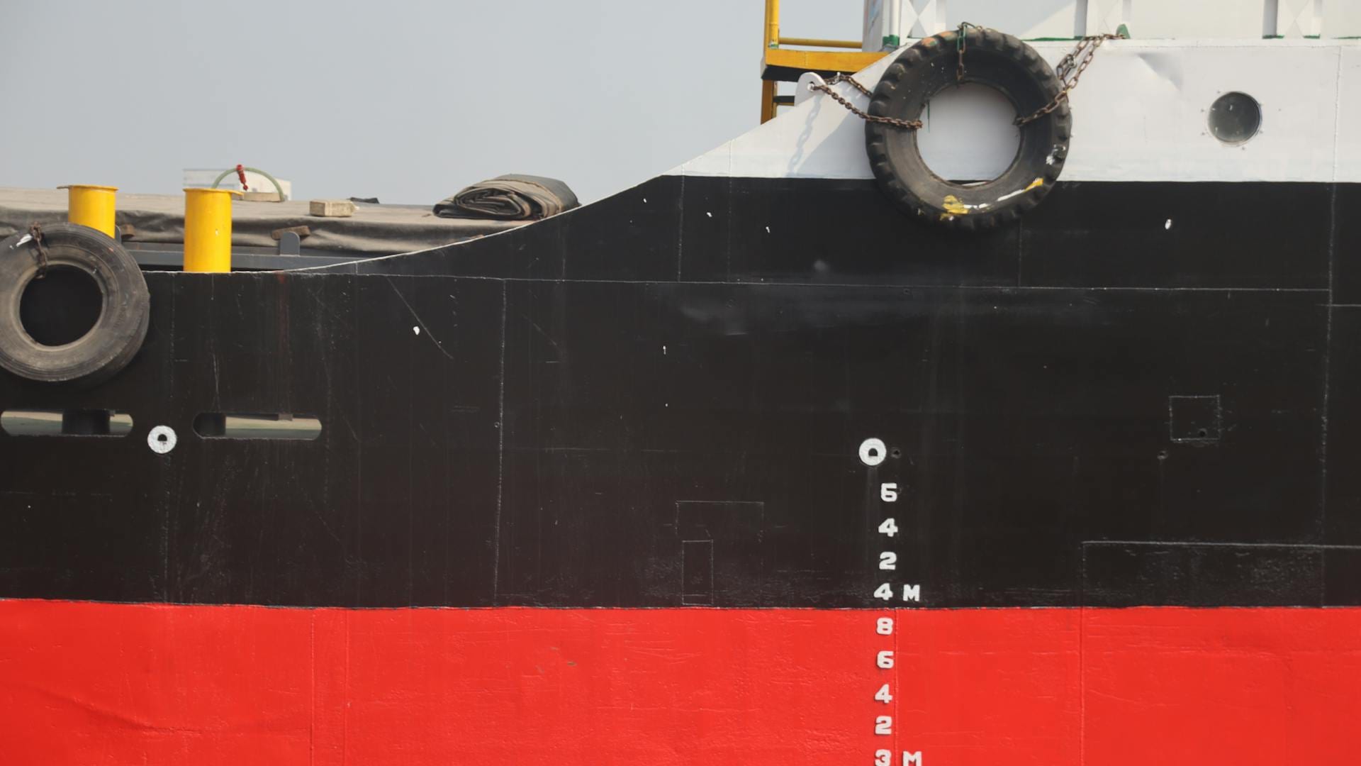 Close-up of a ship's hull with red anti-fouling paint and load-line markings